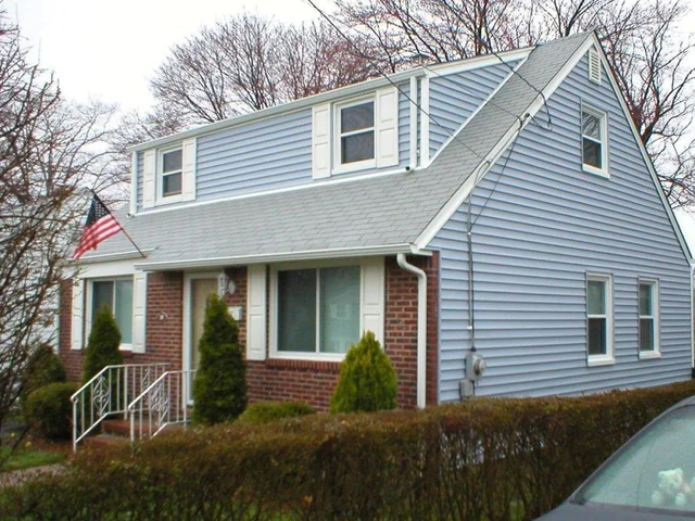 Blue-sided cape with white trim, a brick front and a new roof