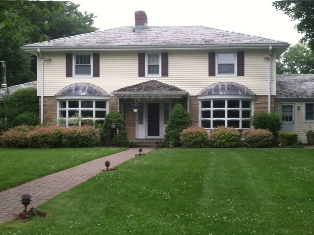 Cream colonial with bay windows and a new gray roof