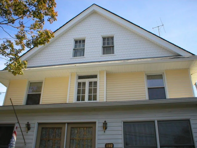 Steep cream-sided gable home with a new dark asphalt shingle roof