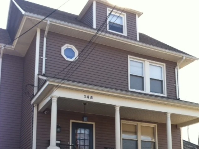 Gray foursquare with an oval window and white porch columns