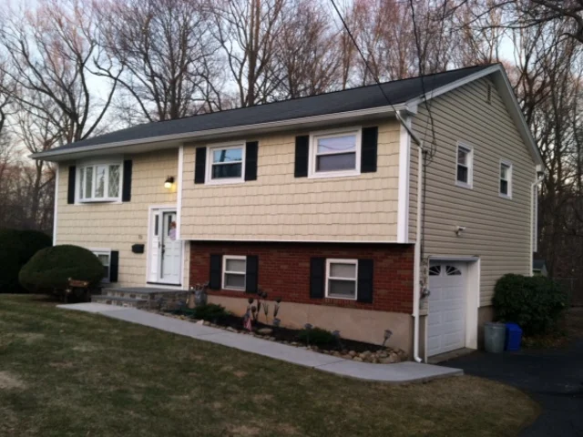 Split-level home with cream siding over brick and a new roof
